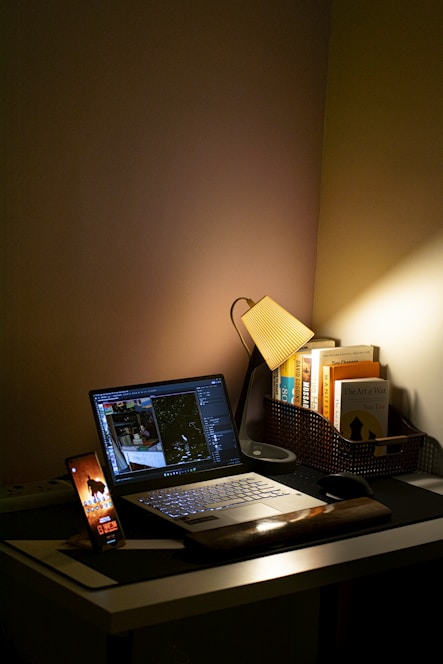 Dark-themed workspace with a sleek laptop, smartphone, and gadgets glowing softly under ambient lighting