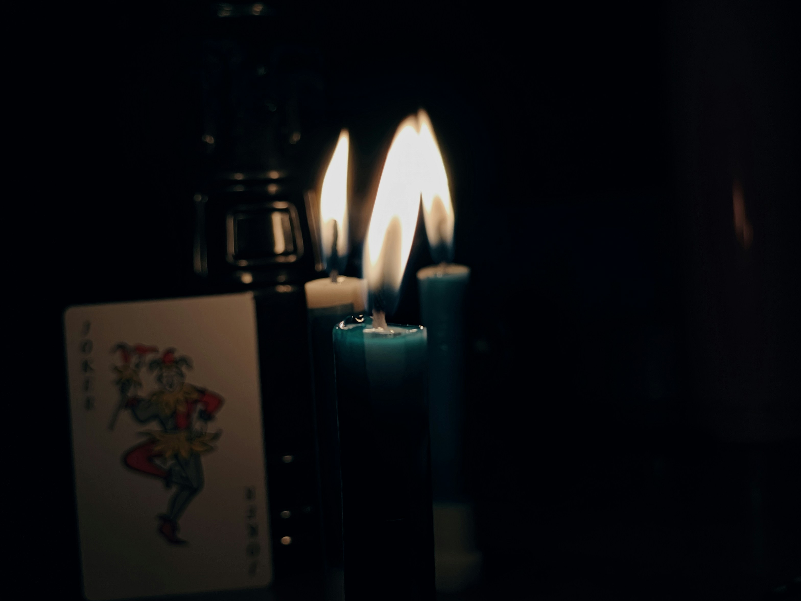 Three lit candles in dark room