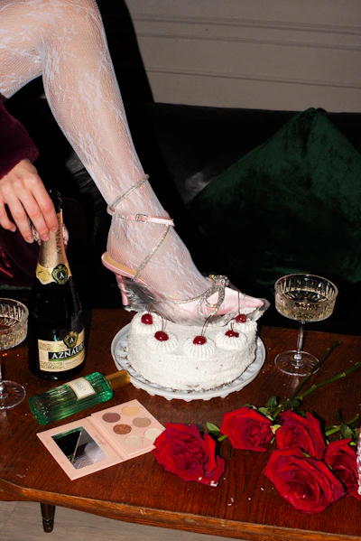 a woman in high heels is pouring champagne into a cake
