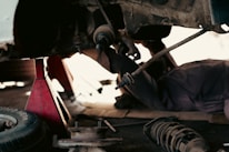 A mechanic installing a suspension part on a car in a bright garage.