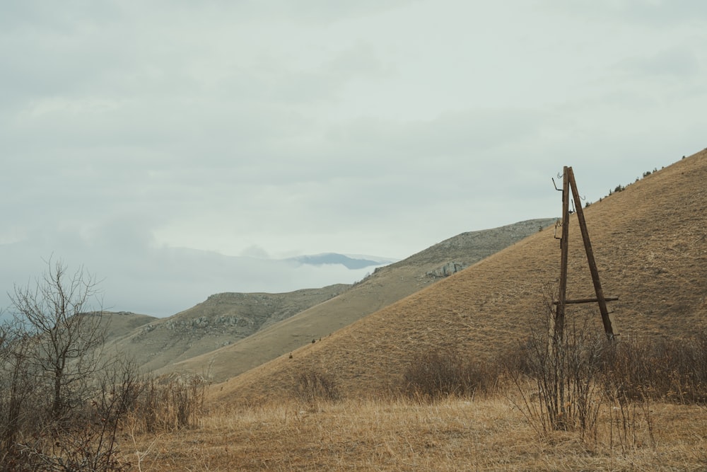 a wooden structure in a field with mountains in the background