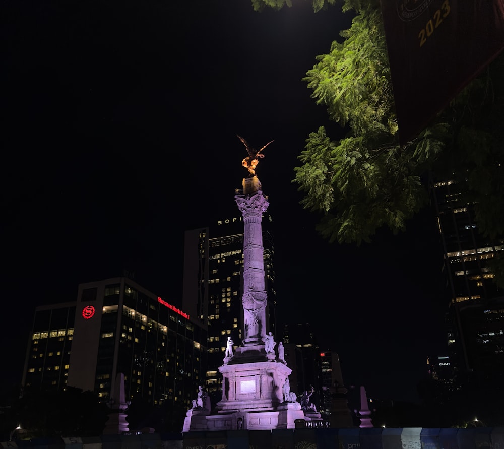 Una estatua en medio de una ciudad por la noche