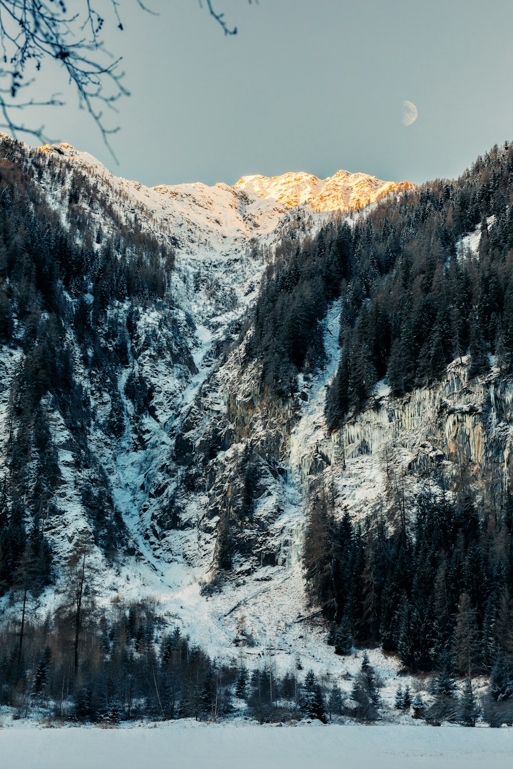 a snow covered mountain with a full moon in the distance