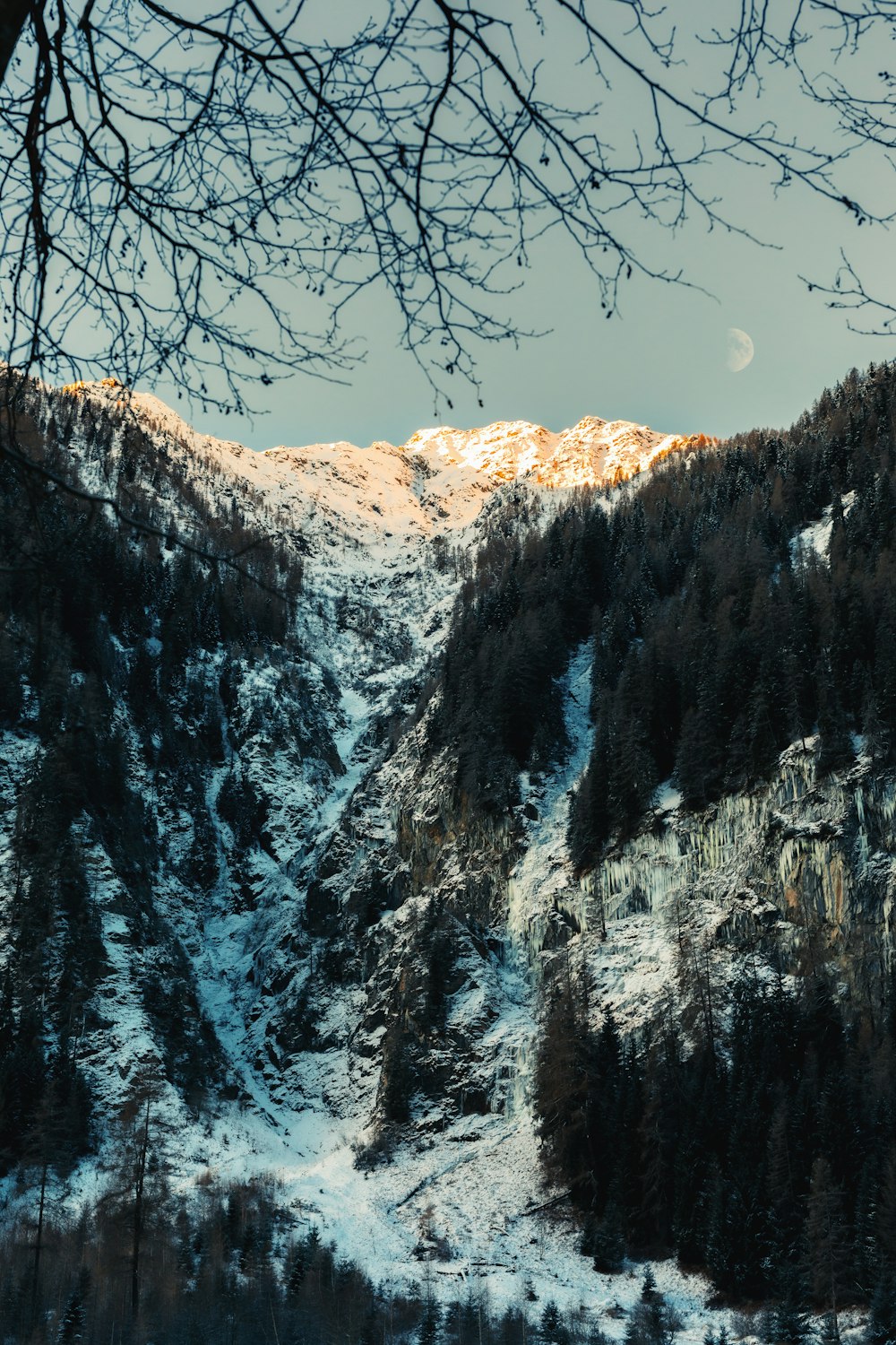 a snow covered mountain with a full moon in the distance