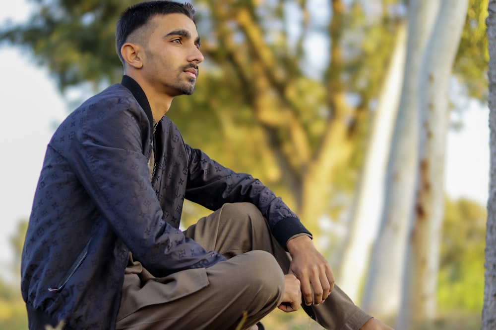 a man sitting on the ground next to a tree