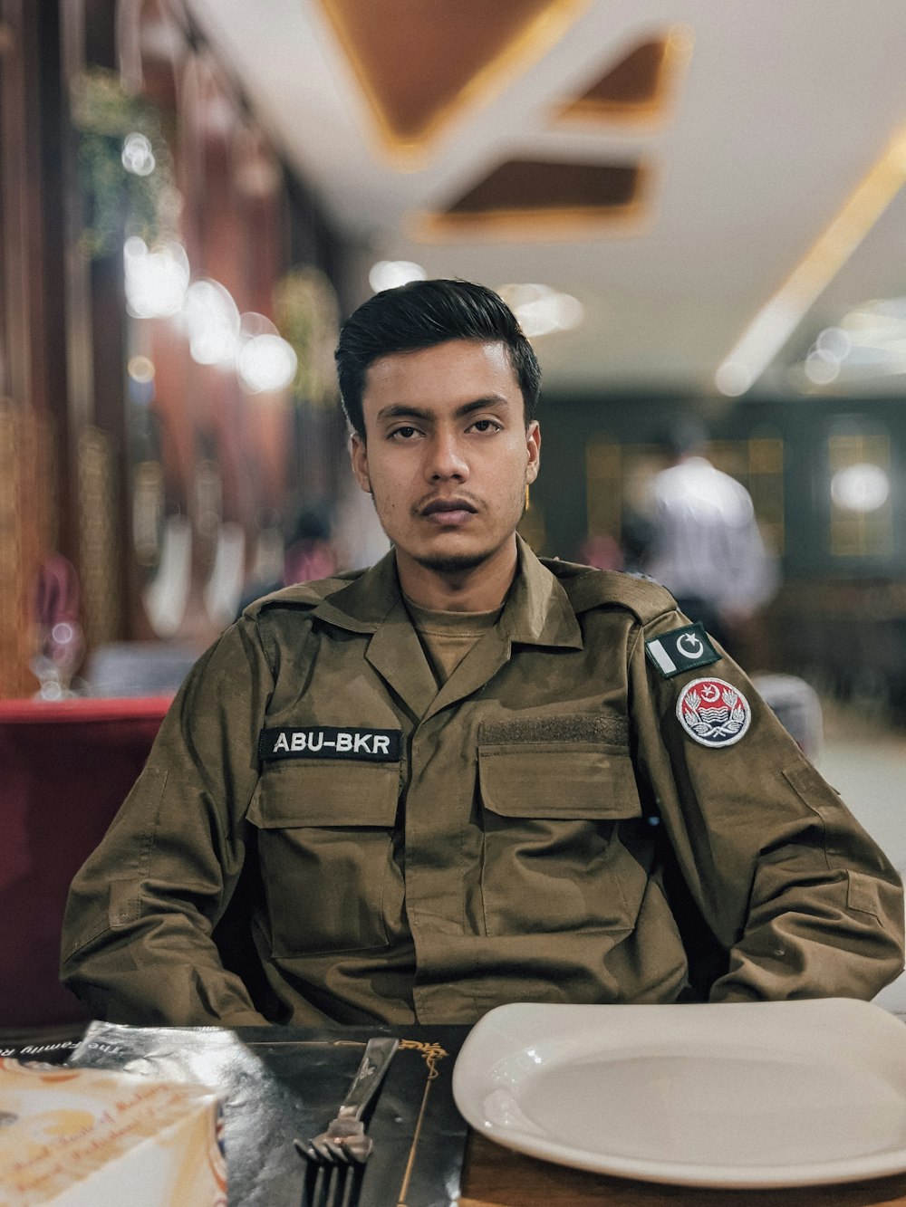 a man in uniform sitting at a table with a plate of food