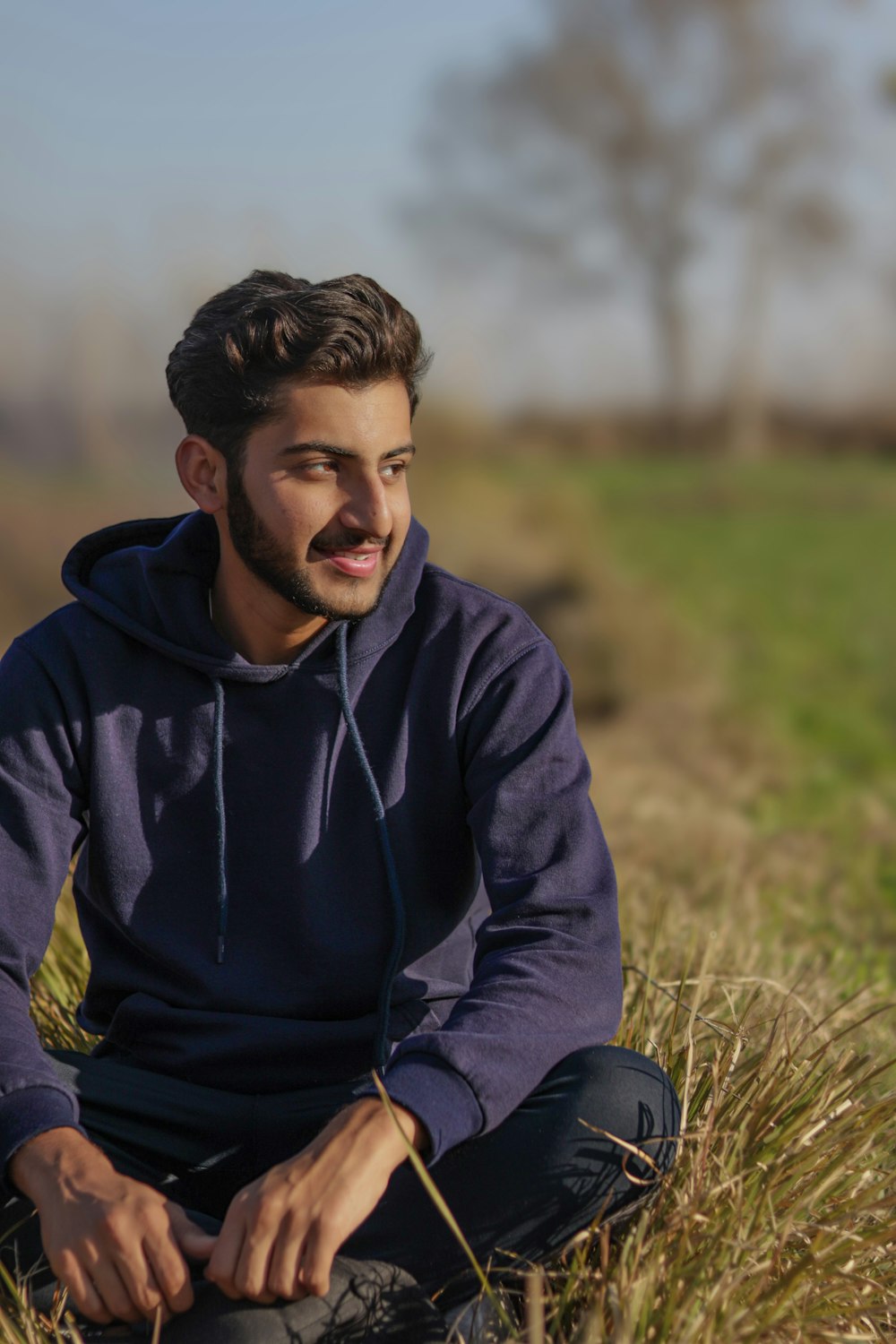 a man sitting in a field with a frisbee in his hand