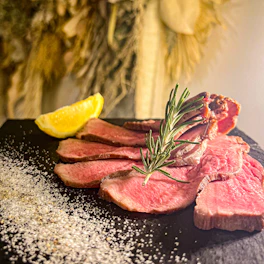Elegant presentation of Wagyu short ribs on a slate plate with wine tinto accents.
