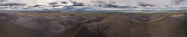 Panoramic shot of the volcanic landscape on the Lava Tour route with a jeep in the foreground.
