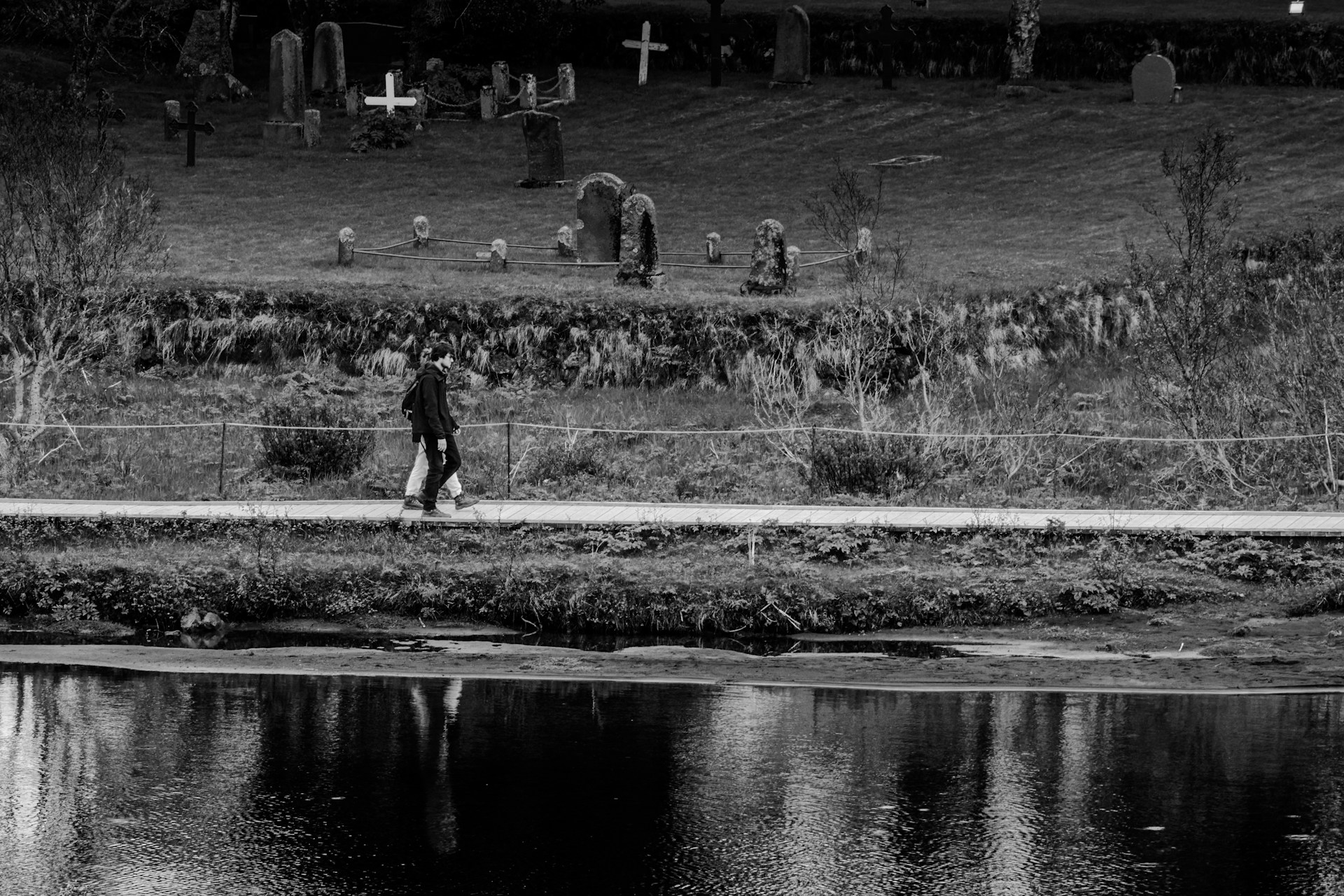 a black and white photo of a person walking across a bridge
