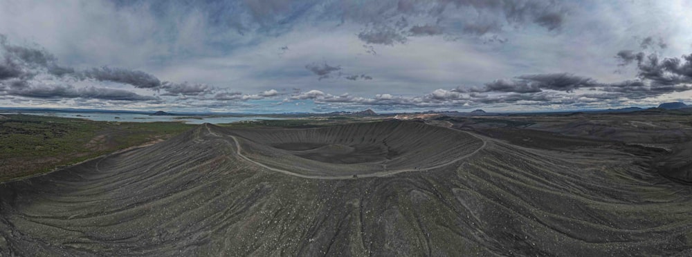 a panoramic view of a dirt field with mountains in the background