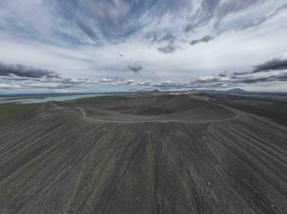 an aerial view of a dirt field with clouds in the sky