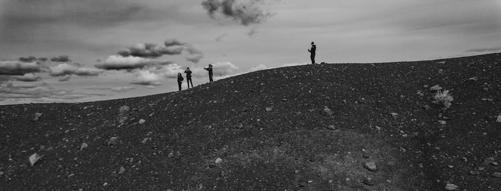 a black and white photo of three people standing on a hill