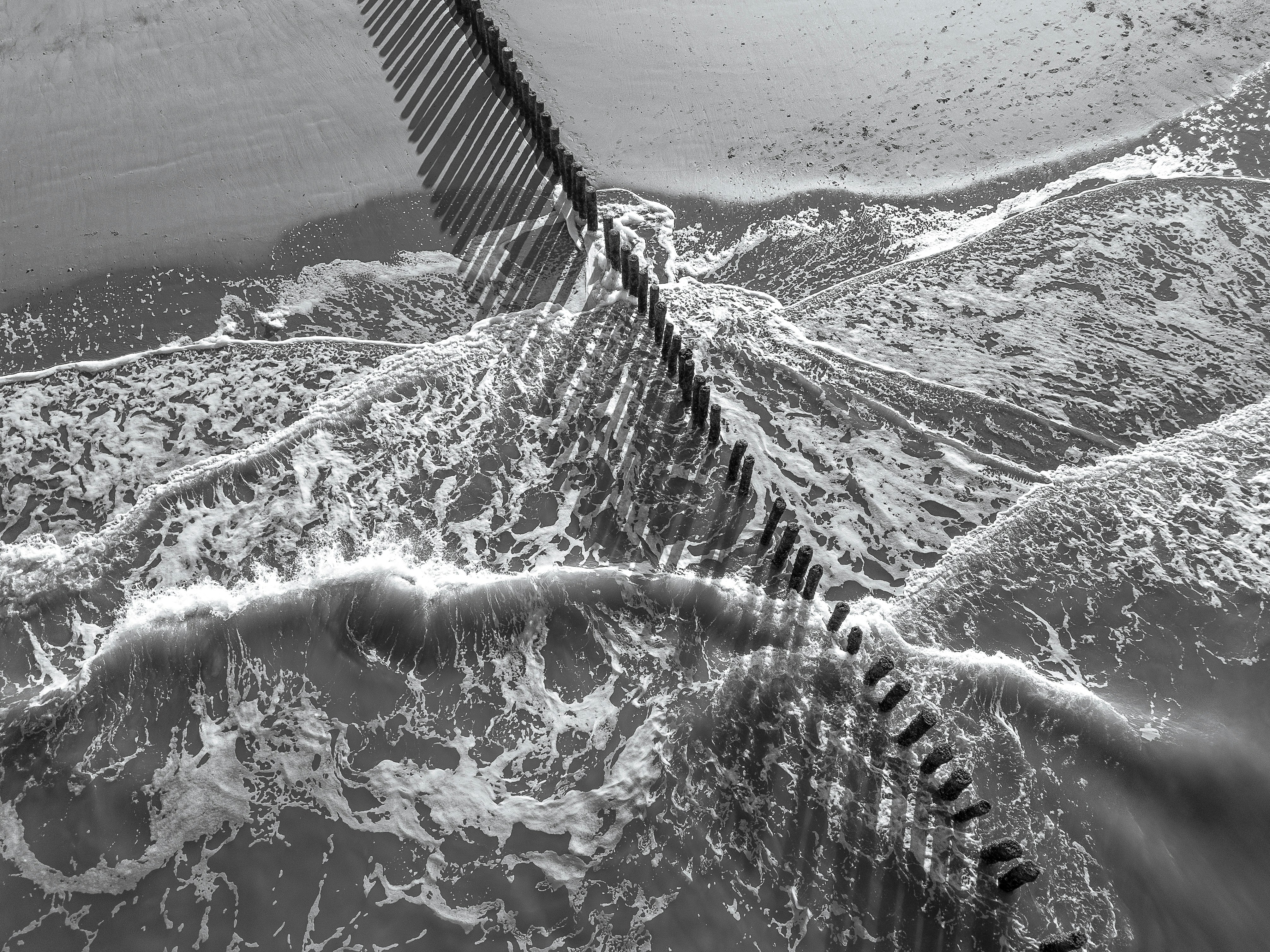 a black and white photo of a fence in the water