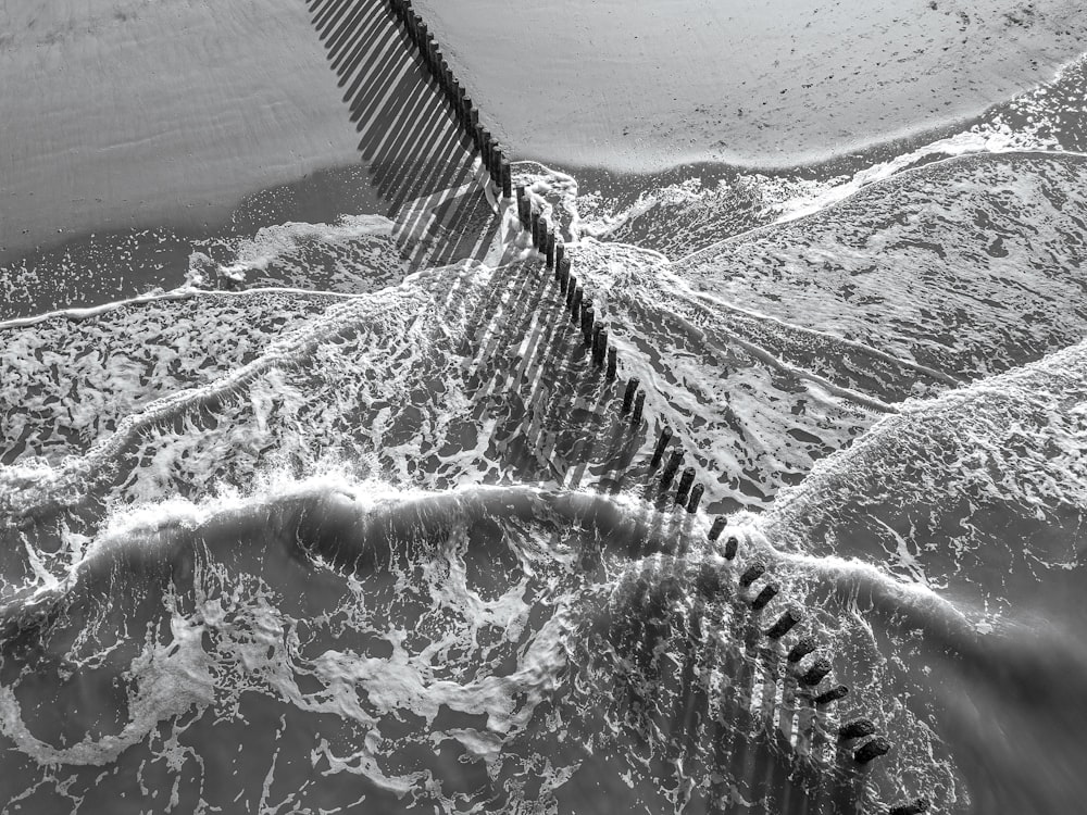 a black and white photo of a fence in the water