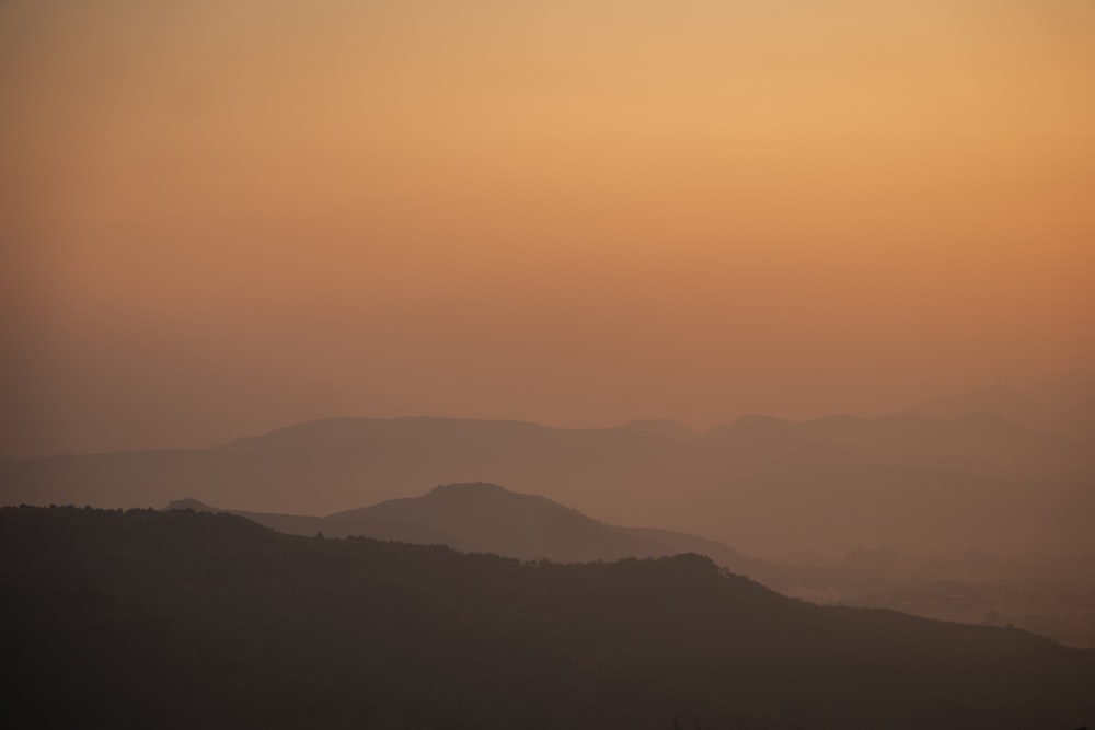 the sun is setting over a mountain range