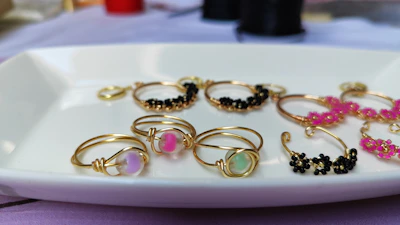 An elegant display of rings and bracelets arranged artfully on a white marble tray accented with orange details