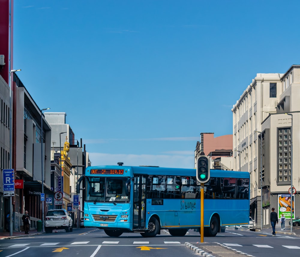 a blue bus driving down a street next to tall buildings