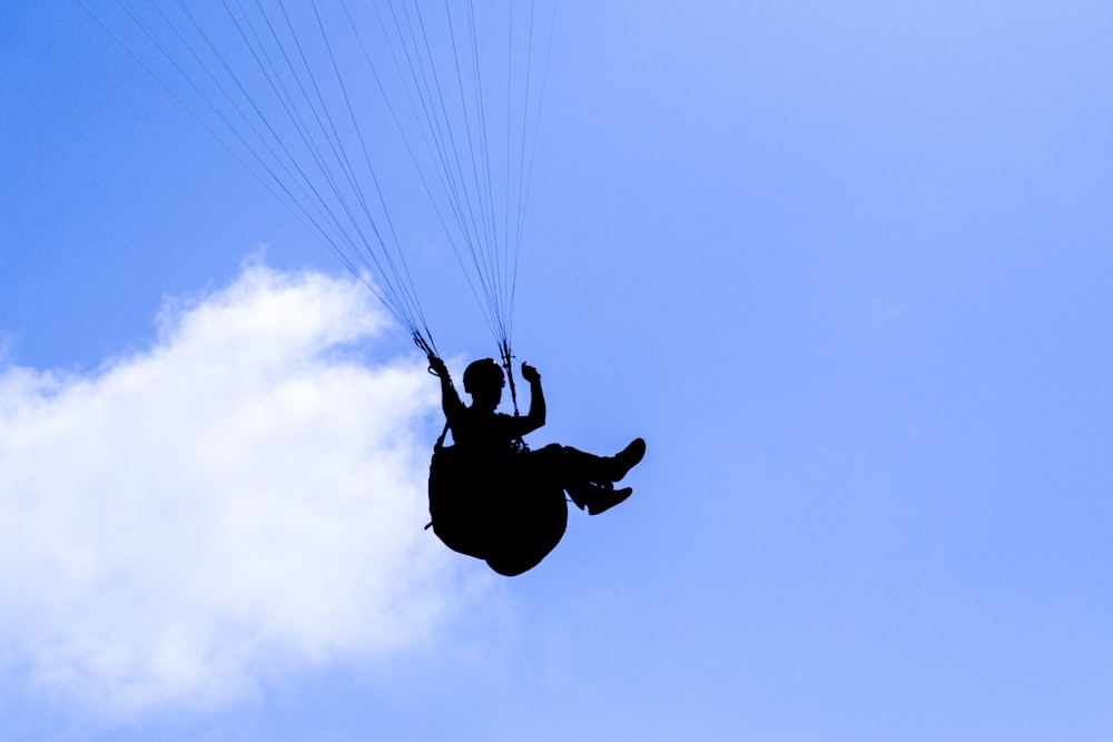 a person flying through the air while holding onto a parachute