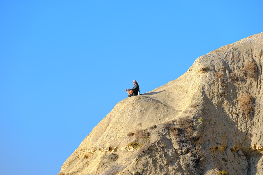 a man sitting on top of a large rock