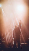 An artist in costume, illuminated by warm stage lights, preparing for their role.