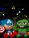 Two plush toys resembling superhero characters with one in blue and red, holding a shield, and another in green with an angry expression. They are displayed against a dark background with some blurred lights.