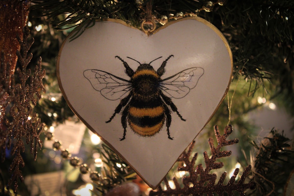 a heart shaped ornament with a bee on it