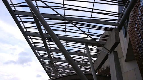 Steel beams being installed on a modern building frame under a clear sky