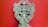 An intricately carved wooden object with floral patterns, ornate scrolls, and symmetrical design against a solid red background. The craftsmanship displays a vintage and artistic feel, with attention to detail in the carvings.