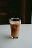 A tall glass of iced coffee with creamy swirls and condensation on the glass.