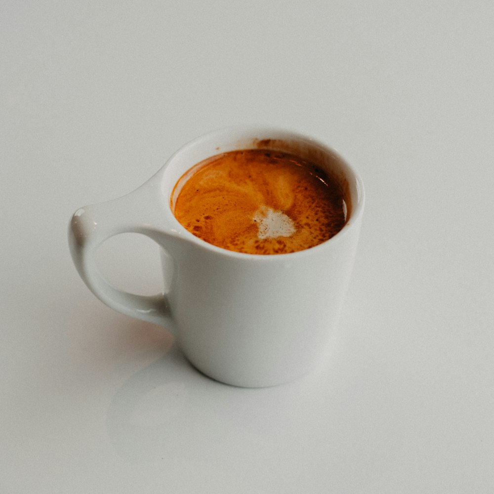 a white cup of coffee on a white table