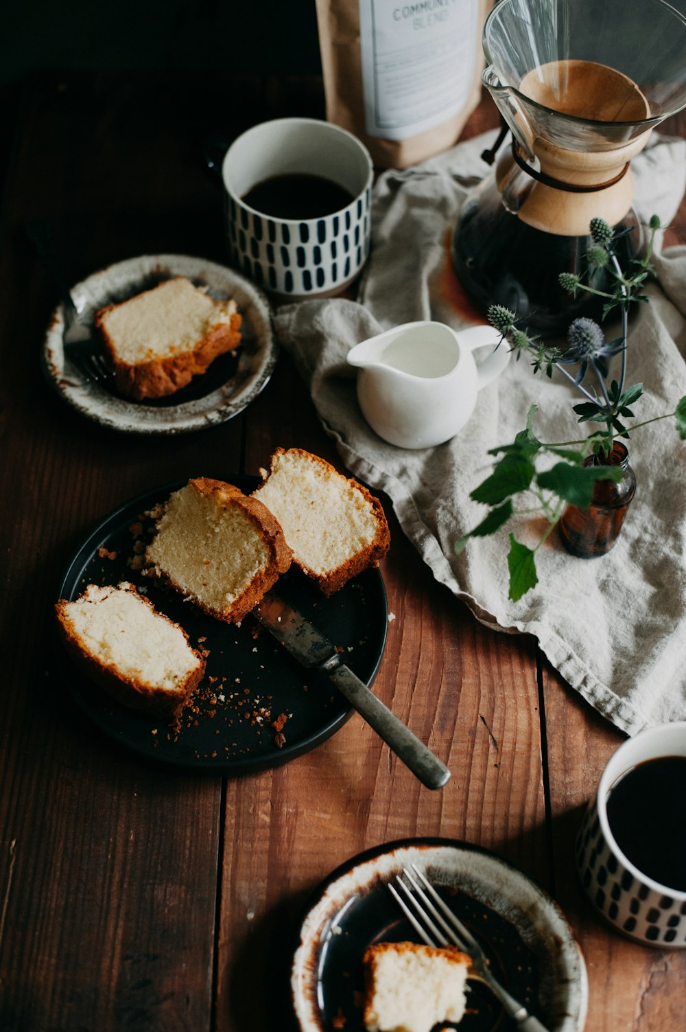 a table topped with slices of cake next to cups of coffee