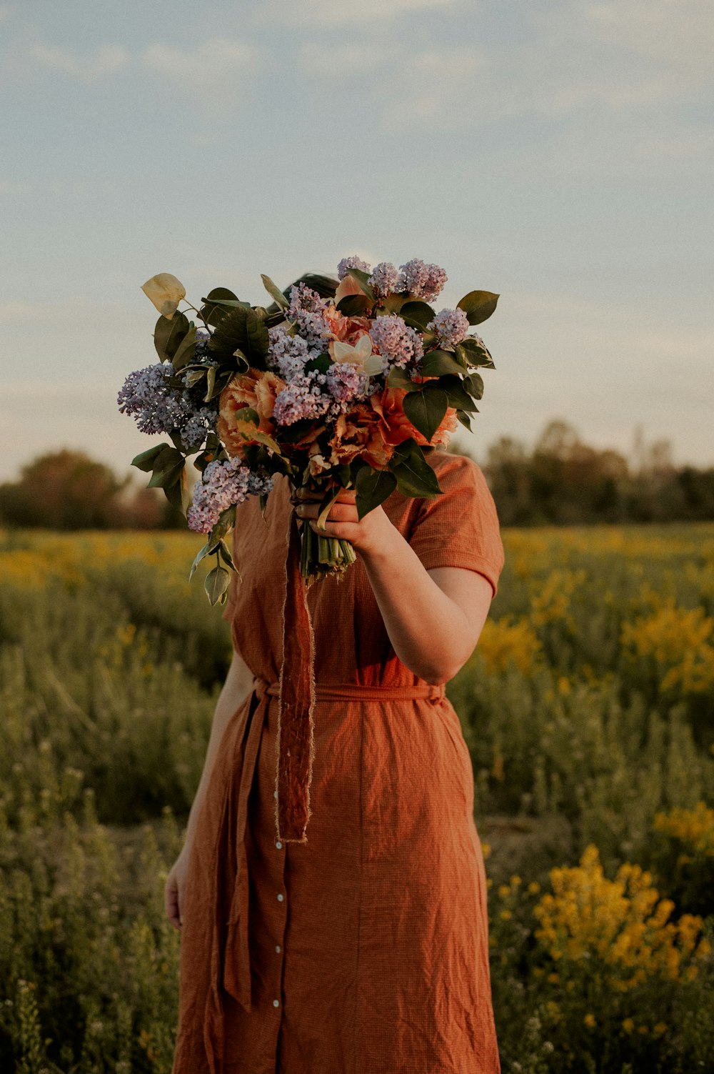 a woman in an orange dress holding a bouquet of flowers