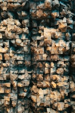 A detailed view of a textured surface composed of numerous interlocking stone-like cubes arranged in a grid pattern. The surface has a three-dimensional appearance with varying depths and shadows, giving it a rugged, geological look.