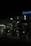 A dimly lit gas station at night featuring several gas pumps under a canopy with the logo partially visible. The station is mostly dark, with some interior lighting emanating from the convenience store in the background.
