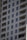 A tall residential apartment building with multiple floors and uniform balconies. The facade is a light color, with dark-framed windows evenly distributed across the structure. Each apartment appears to have large, floor-to-ceiling windows and minimalistic railings.