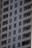 A tall residential apartment building with multiple floors and uniform balconies. The facade is a light color, with dark-framed windows evenly distributed across the structure. Each apartment appears to have large, floor-to-ceiling windows and minimalistic railings.