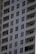 A tall residential apartment building with multiple floors and uniform balconies. The facade is a light color, with dark-framed windows evenly distributed across the structure. Each apartment appears to have large, floor-to-ceiling windows and minimalistic railings.