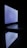 A laptop is open in a dark environment with its screen glowing and its reflection visible on the surface below.