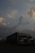 A line of freight trucks parked at a busy warehouse at dawn.