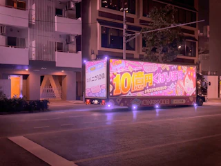 Night shot of an illuminated truck ad shining brightly on a city street.