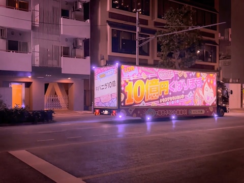 Mobile advertising truck with bright LED screens displaying colorful visuals at night.