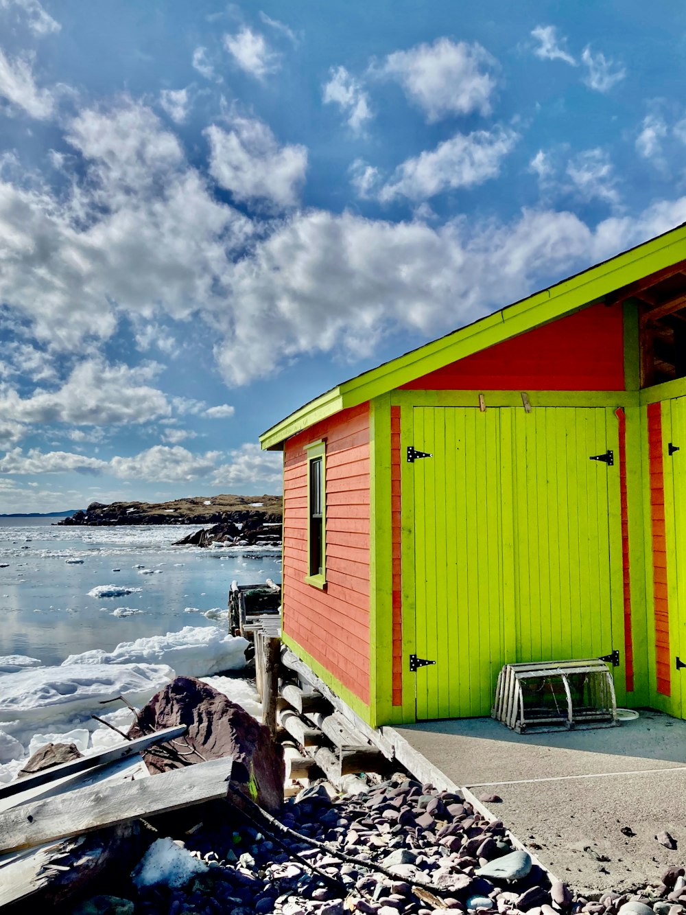 a small red and green building next to the ocean