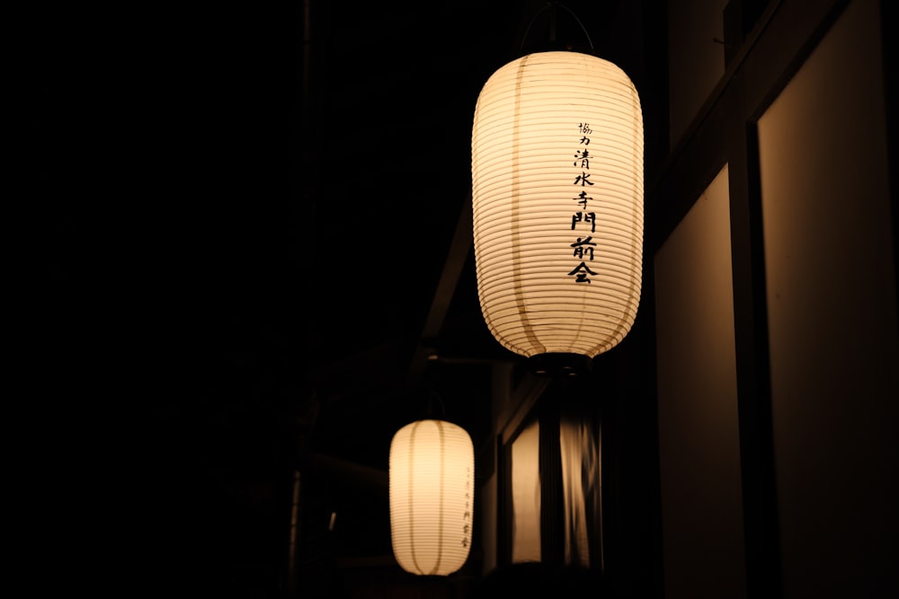 a couple of white lanterns hanging from a ceiling