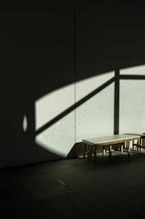 Minimalist wooden bench placed in a sunlit corner with simple decoration