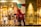The image features a storefront with colorful, stylized graphics of people shopping and a decorated Christmas tree. A large depiction of Santa Claus is on one side. To the right, a mannequin wearing a sweater and long skirt is displayed against a wooden wall.