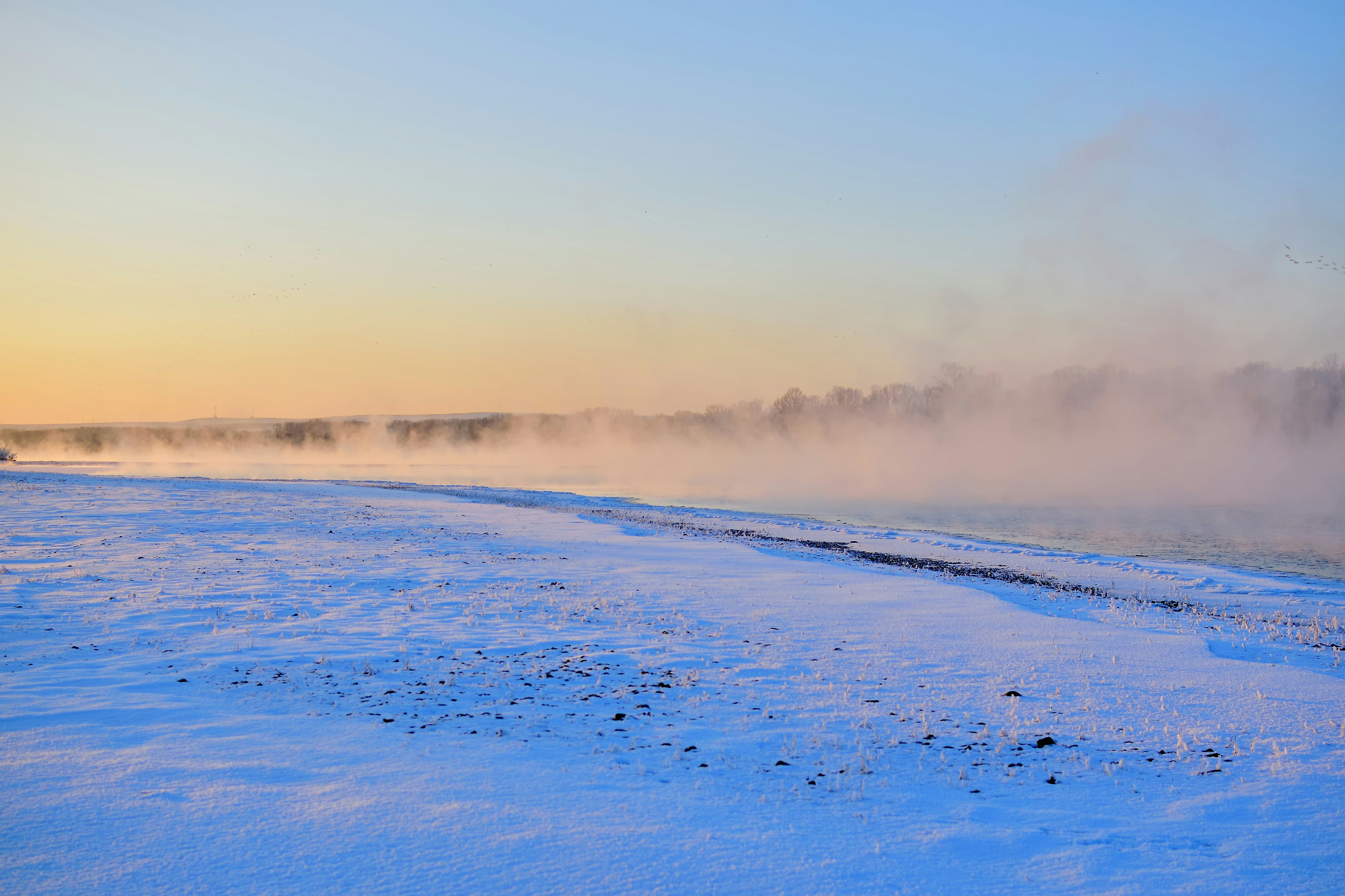a snow covered field with steam rising from the ground