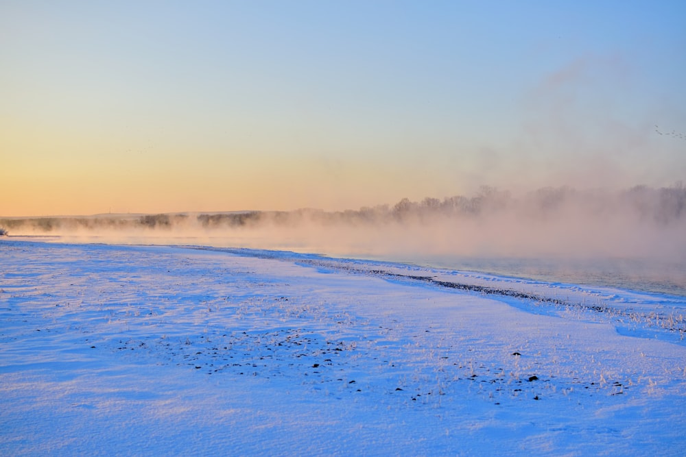 a snow covered field with steam rising from the ground