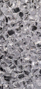 Close-up of clear ice cubes being packed into 3 kg bags at a modern facility.