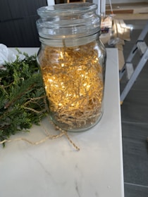 A vintage apothecary jar filled with shimmering golden incense dust, glowing softly in candlelight.